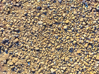 Detailed view of a textured ground covered in small pebbles and stones in a sunlit outdoor environment