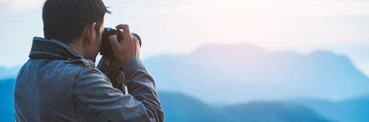 The photographer with jacket taking photo by a camera in a mountains. Creative professional photographing.Travel, hobby and active lifestyle concept