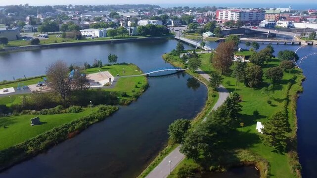 Aerial view of an urban family park with games on islands linked by trails and footbridges along the Matane River in Matane, Quebec