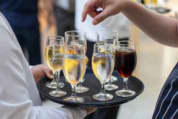 Waiter serving a variety of drinks on a tray at a lively indoor event in the afternoon