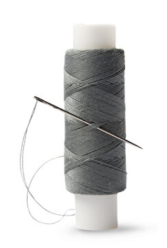 Thread bobbin and needle on white background
