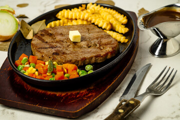 Steak, Fries, and Vegetables on a Sizzling Plate