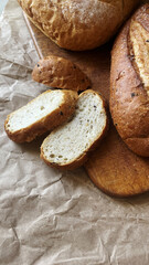 Naklejka premium Close up of freshly baked delicious organic homemade wholemeal bread with crispy crust and cut slices on wooden board in bakery kitchen