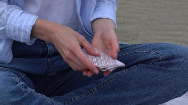 Hands of a young woman shuffling cards for the next game. Entertainment concept, having fun, card board games, solitaire, poker