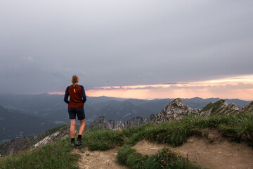 Obraz premium Frau steht im Sonnenuntergang am Nebelhorn im Allgäu