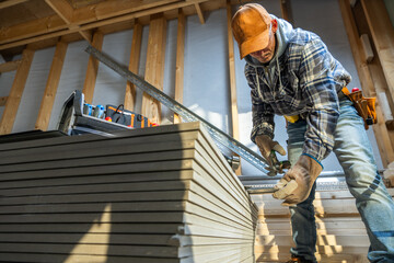 Carpenter Measuring Materials in a Construction Workshop During Early Morning Hours