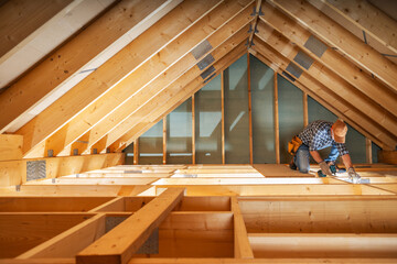 A Carpenter Working on an Attic Renovation Project With Natural Light Streaming Through the Beams