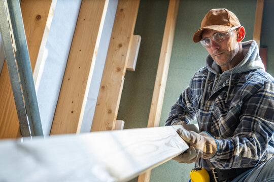 Carpenter Measuring Wood Carefully Inside a Construction Site During Daylight Hours