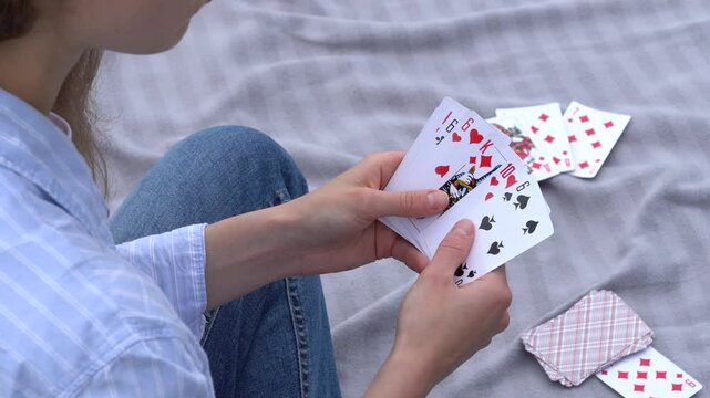 A young woman playing cards chooses how to move, looks at the trump card, and puts the card on the deck outdoors. Concept of board card games, getting fun, entertainment
