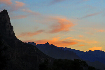 Sunset over the distant mountains with a part of the Watchman, one of Zion national Parks iconic peaks in the foreground