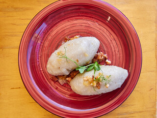 cepelins stuffed with minced meat on a red plate © pawel_ka_foto