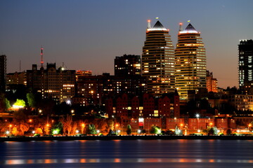 View of beautiful modern buildings, skyscrapers and towers of night big city are reflected in River...