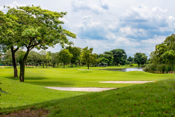 Fototapeta premium a white golf ball on a tee and a green field ready to be hit with a wood golf stick as a start to a game of golf.