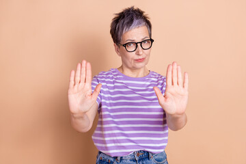 Photo of confident adorable senior woman wear striped stylish clothes isolated on beige color background