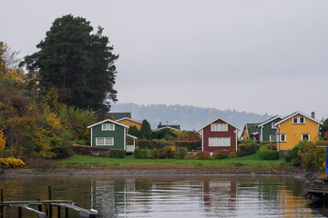 Obraz premium Oslo, Norway - October 20, 2024: Oslofjord (Oslofjorden), view of summer houses and cottages. Frame houses for recreation. Hut among the forest and rocks. Multicolored private houses.