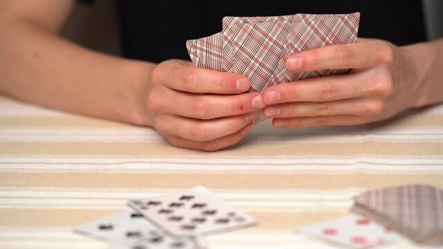 Close-up of the hand of a young woman playing cards, chooses how to move, looks at the trump card, and puts the card on the deck at the table. Concept of board card games, getting fun, entertainment