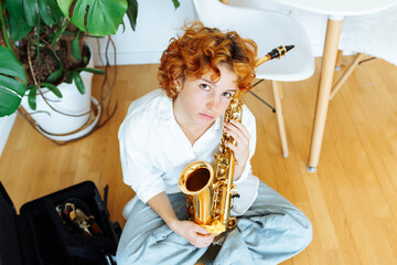 portrait young red-haired attractive woman playing saxophone,