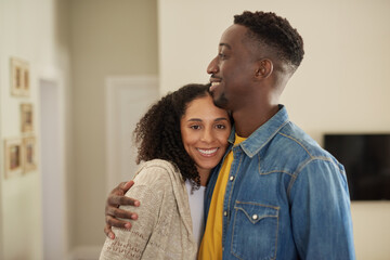 Fototapeta premium Loving young multiracial couple smiling while standing together in their living room