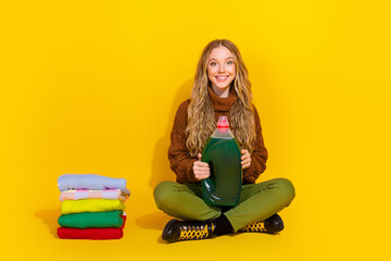 Full size photo of pretty young woman hold washing laundry detergent isolated on yellow color...