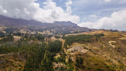Obraz premium beautiful landscape in the South American highlands with large mountains surrounded by nature and trees, on a sunny day with large white clouds in the blue sky