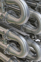 A lot of shiny curved stainless steel pipes of industrial equipment cooling system