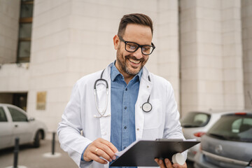 man doctor read information from clipboard stand in front building