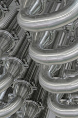 A lot of shiny curved stainless steel pipes of industrial equipment cooling system