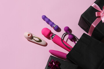 Bag with sex toys and gifts on pink background