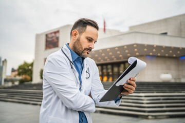 concentrated man doctor read information from clipboard outdoor