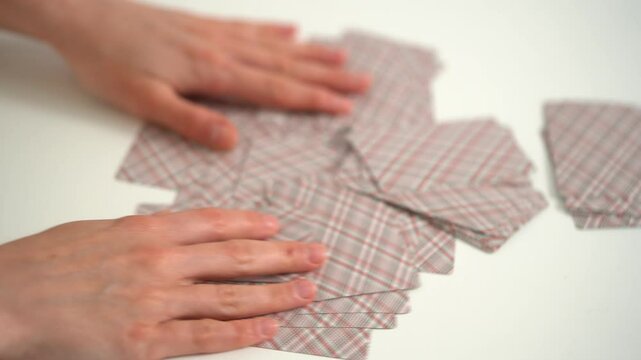 Hands of a young woman collect and shuffle cards from the table for the next game. Entertainment concept, having fun, card board games