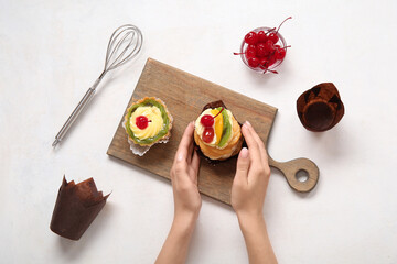 Female confectioner with tasty cakes on white background
