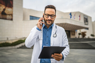 Adult man doctor hold clipboard and talk on mobile phone during break