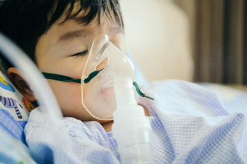 Boy 4 years old , inhale medication by inhalation mask to cure Respiratory Syncytial Virus (RSV) on hospital bed. Admitted patient boy inhalation therapy.