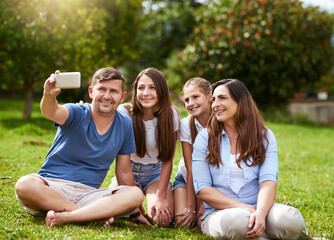 Parents, children and smile for selfie in park with bonding, happy memory or relax on grass for holiday. Family, people and photography in nature for social media post, profile picture update or love