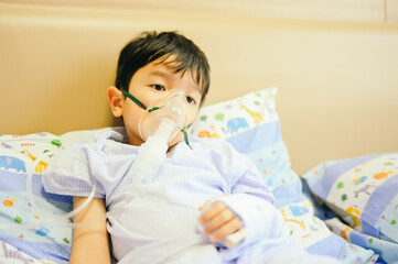 Boy 4 years old , inhale medication by inhalation mask to cure Respiratory Syncytial Virus (RSV) on hospital bed. Admitted patient boy inhalation therapy.