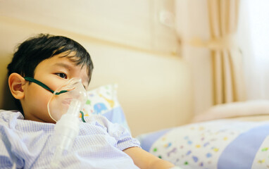 Boy 4 years old , inhale medication by inhalation mask to cure Respiratory Syncytial Virus (RSV) on hospital bed. Admitted patient boy inhalation therapy.