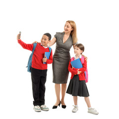 Obraz premium Mature teacher with little pupils taking selfie on white background