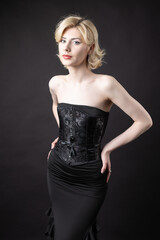 Expressive young blonde under a bob in the studio. In a black corset and dress.