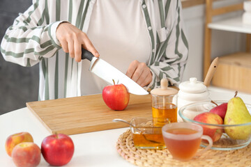 Woman cutting apples at table in kitchen