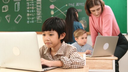 Cute boy coding engineering prompt while attractive girl drawing picture at blackboard. Caucasian...