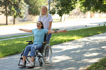 Fototapeta premium Young woman in wheelchair and her mother spending time together outdoors