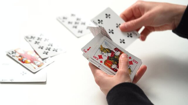 Close-up of a young woman's hand dealing a classic solitaire deck of cards at a table. The concept of board card games, having fun, entertainment, poker.