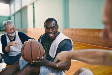 Senior men taking a break from playing basketball in an indoor gym