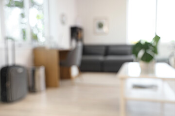 Blurred view of living room with modern grey sofa, coffee table and workspace
