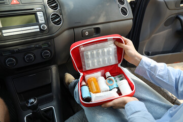 Woman on passenger seat holding open first aid kit in car