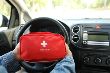 Male driver holding first aid kit in car, closeup