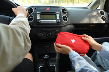 Woman on passenger seat holding first aid kit in car