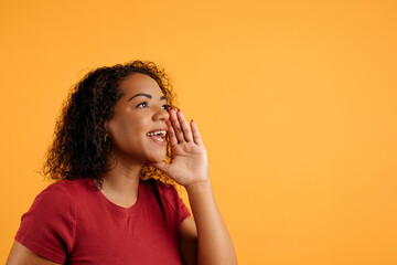 Positive Young Black Woman With Hand Near Mouth Making Announcement, Cheerful African American Female Sharing News Or Information While Standing Isolated On yellow Background, Panorama, Copy Space