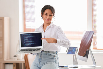 Young African-American QA engineer pointing at laptop with programming code in office