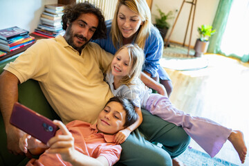 Happy family taking group selfie on couch at home